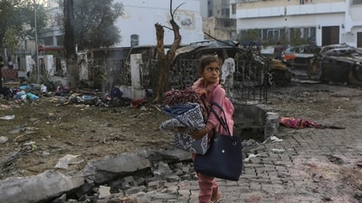 Israel-Hamas War: A girl carries blankets as she walks past the site of a deadly explosion at al-Ahli hospital in Gaza City. (AP)