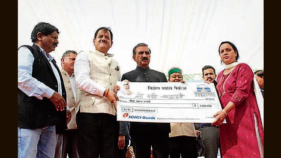 Himachal CM Sukhvinder Singh Sukhu hands a cheque for ₹3 lakh under the rehabilitation scheme in Kullu on Saturday. (Aqil Khan/HT)
