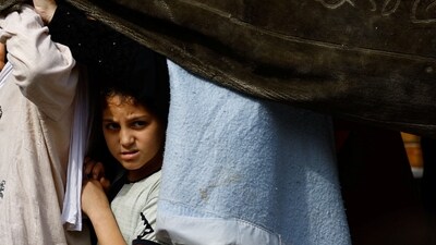 Israel-Hamas War: A child looks on as Palestinians queue to buy bread from a bakery, amid shortages of food supplies and fuel, as the conflict between Israel and Palestinian Islamist group Hamas continues, in Khan Younis. (Reuters)