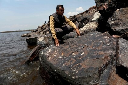 Archaeologist Jaime Oliveira, from the National Historical and Artistic Heritage Institute (Iphan), shows ancient rock engravings that reappeared in the region of the Lajes Archaeological Site due to the severe drought. (AFP)