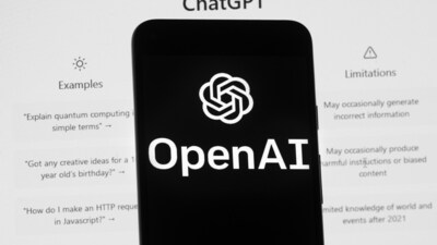 The OpenAI logo is seen on a mobile phone in front of a computer screen which displays the ChatGPT home Screen. (AP)