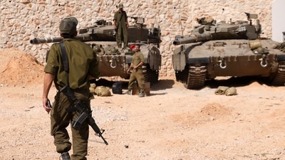 Israeli soldiers gather near Merkava tanks as they man a position at an undisclosed location on the border with Lebanon. (AFP) Israeli soldiers gather near Merkava tanks as they man a position at an undisclosed location on the border with Lebanon. (AFP)