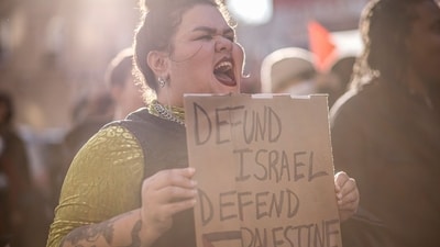 A protestor holds a sign reading "Defund Israel, Defend Palestine" as people rally in support of Palestinians in Brooklyn, New York on October 21, 2023, amid ongoing conflict between Israel and Hamas. (Photo by KENA BETANCUR / AFP) (AFP)