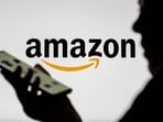 Woman with smartphone seen in front of the Amazon logo.