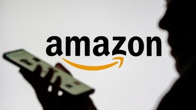 Woman with smartphone seen in front of the Amazon logo. (REUTERS)