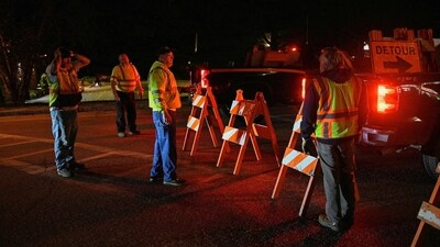 Workers set down detour signs while police organize around Lisbon High School as an active search for a gunman is underway after Lewiston's deadly mass shootings, in Lisbon, Maine, U.S. (REUTERS)