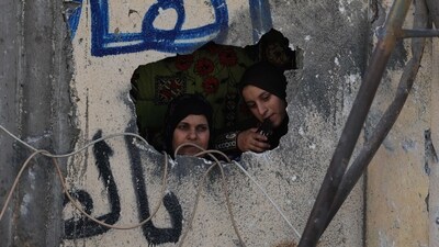 Palestinian women look out from a hole in a damaged wall following Israeli strikes on the Rafah refugee camp in the southern Gaza Strip (AFP) Palestinian women look out from a hole in a damaged wall following Israeli strikes on the Rafah refugee camp in the southern Gaza Strip (AFP)