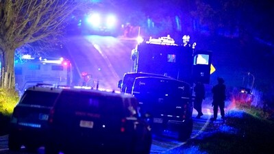 Law enforcement officers, right, stand near armored and tactical vehicles, center, near a property on Meadow Road, in Bowdoin, Maine, (AP) Law enforcement officers, right, stand near armored and tactical vehicles, center, near a property on Meadow Road, in Bowdoin, Maine, (AP)
