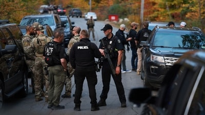 Law enforcement officials gather in the road leading to the home of the suspect being sought in connection with two mass shootings on October 26, 2023 in Bowdoin, Maine. Police are searching for U.S. Army Reservist Robert Card, 40, who is wanted in the shooting deaths of 18 people at a bowling alley and a bar last night in nearby Lewiston. At least 13 others were wounded in the rampage. (Getty Images via AFP) Law enforcement officials gather in the road leading to the home of the suspect being sought in connection with two mass shootings on October 26, 2023 in Bowdoin, Maine. Police are searching for U.S. Army Reservist Robert Card, 40, who is wanted in the shooting deaths of 18 people at a bowling alley and a bar last night in nearby Lewiston. At least 13 others were wounded in the rampage. (Getty Images via AFP)