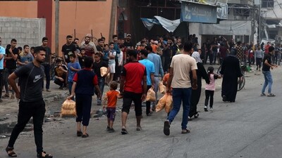 Israel-Hamas War: People carry bags of bread as others queue in front of a bakery, in the aftermath of Israeli strikes in Gaza City. (AFP) Israel-Hamas War: People carry bags of bread as others queue in front of a bakery, in the aftermath of Israeli strikes in Gaza City. (AFP)
