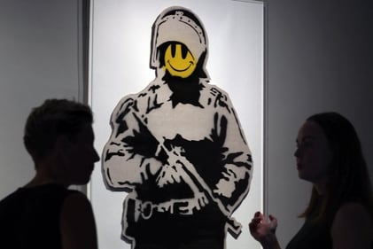 Visitors look at "Smiling Copper" by British artist Banksy, at the Forbidden Art Museum in Barcelona on October 26, 2023. (Photo by LLUIS GENE / AFP)