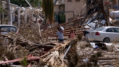 Mexico Hurricane: People walk next to rubble and damaged trees in the aftermath of Hurricane Otis, in Acapulco, Mexico. (Reuters)