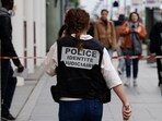 A French police officer wears a jacket, identifying herself as "Police identite judiciaire"), while walking from a metro station. A French police officer wears a jacket, identifying herself as "Police identite judiciaire"), while walking from a metro station.
