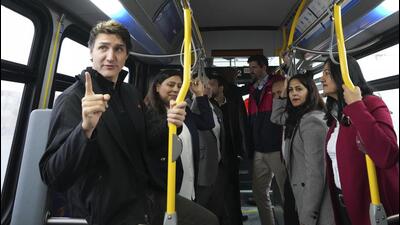 Canada's Prime Minister Justin Trudeau (left) rides on a new all electric public transportation bus before making an housing announcement in Brampton, Ontario, on October 20. (AP)