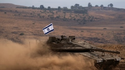An Israeli soldier drives a tank with an Israeli flag on the top to a staging area near the Israeli border with Lebanon, (AP) An Israeli soldier drives a tank with an Israeli flag on the top to a staging area near the Israeli border with Lebanon, (AP)