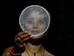 A married woman looks at the moon through a sieve as part of a ritual before breaking her fast during Karva Chauth festival in Jammu. 