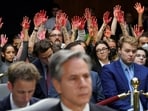 Anti-war protesters raise their "bloody" hands behind US Secretary of State Antony Blinken during a Senate Appropriations Committee hearing