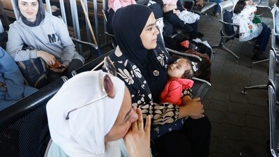 A woman holds a baby, as Palestinians with dual citizenship wait at the Rafah border crossing with Egypt, in the hope of getting permission to leave Gaza, amid the ongoing conflict between Israel and Palestinian Islamist group Hamas, in Rafah in the southern Gaza Strip. (REUTERS)