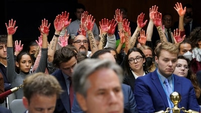Anti-war protesters raise their "bloody" hands behind US Secretary of State Antony Blinken during a Senate Appropriations Committee hearing (REUTERS)