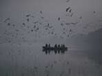 A man sitting in a boat feeds seagulls on the Yamuna River in Heavy smog as Air pollution rises in Capital/NCR in New Delhi, India, on Thursday, November 2, 2023. A man sitting in a boat feeds seagulls on the Yamuna River in Heavy smog as Air pollution rises in Capital/NCR in New Delhi, India, on Thursday, November 2, 2023.