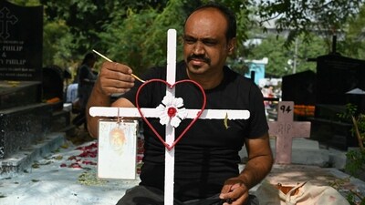 A Catholic Christian decorates a cross on the grave of a family member at a cemetery during All Souls Day in Hyderabad. (AFP)
