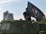 A man mounts a flag of Wagner group on top of an old tank exhibited at the Leninist Komsomol park in Donetsk, Russian-controlled Ukraine, on October 1, 2023, (Photo by STRINGER / AFP) A man mounts a flag of Wagner group on top of an old tank exhibited at the Leninist Komsomol park in Donetsk, Russian-controlled Ukraine, on October 1, 2023, (Photo by STRINGER / AFP)