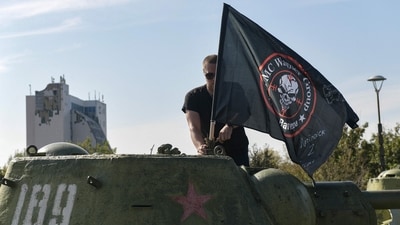 A man mounts a flag of Wagner group on top of an old tank exhibited at the Leninist Komsomol park in Donetsk, Russian-controlled Ukraine, on October 1, 2023, (Photo by STRINGER / AFP) (AFP) A man mounts a flag of Wagner group on top of an old tank exhibited at the Leninist Komsomol park in Donetsk, Russian-controlled Ukraine, on October 1, 2023, (Photo by STRINGER / AFP) (AFP)
