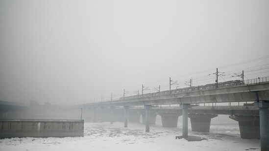 A metro train rides over a river choking with foul froth, amid heavy smog conditions in New Delhi on November 4, 2023. A metro train rides over a river choking with foul froth, amid heavy smog conditions in New Delhi on November 4, 2023.