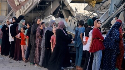 Palestinian women line up to buy fresh bread next to destroyed buildings at the Nuseirat refugee camp in the central Gaza Strip on November 4, 2023. (AFP) Palestinian women line up to buy fresh bread next to destroyed buildings at the Nuseirat refugee camp in the central Gaza Strip on November 4, 2023. (AFP)