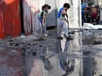 Palestinian children mop outside their home after an Israeli bombardment in the Maghazi refugee camp in the Gaza Strip on Sunday, Nov. 5, 2023. (AP Photo/Hatem Moussa)