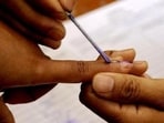A polling official marks a voter with indelible ink prior to casting a ballot inside a polling station at Bungthuam in Mizoram.