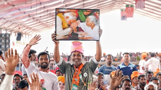 A supporter holds a painting of Prime Minister Narendra Modi and his mother during an election rally ahead of the Chhattisgarh assembly elections A supporter holds a painting of Prime Minister Narendra Modi and his mother during an election rally ahead of the Chhattisgarh assembly elections