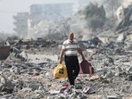Palestinians walk by the buildings destroyed in the Israeli bombardment on al-Zahra, on the outskirts of Gaza City. Palestinians walk by the buildings destroyed in the Israeli bombardment on al-Zahra, on the outskirts of Gaza City.