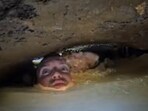 The image shows a man exploring a water-filed cave. The image shows a man exploring a water-filed cave.