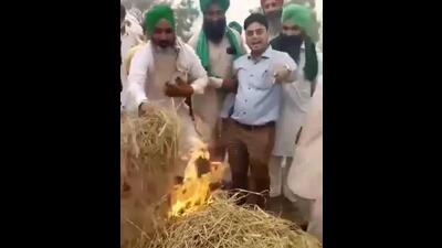 A video grab of farmers holding Punjab PWD sub divisional engineer Hardeep Sagar by the arm and forcing him to torch the paddy residue at Mehma Sarja village in Bathinda district on Friday. (X) A video grab of farmers holding Punjab PWD sub divisional engineer Hardeep Sagar by the arm and forcing him to torch the paddy residue at Mehma Sarja village in Bathinda district on Friday. (X)