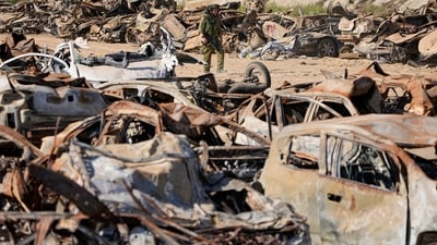 An Israeli soldier inspects charred vehicles burned in the bloody Oct. 7 cross-border attack by Hamas (AP)