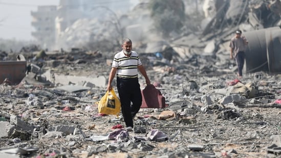 Palestinians walk by the buildings destroyed in the Israeli bombardment on al-Zahra, on the outskirts of Gaza City. (AP)