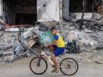 Israel-Hamas War: A Palestinian boy transports his bird on a bicycle past a destroyed building in Rafah in the southern Gaza Strip. Israel-Hamas War: A Palestinian boy transports his bird on a bicycle past a destroyed building in Rafah in the southern Gaza Strip.