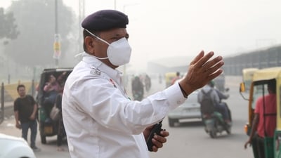 A traffic policeman manages traffic while wearing a mask amidst a thick layer of smog as the air quality goes down to the 'very poor' category in Gurugram on Tuesday. (ANI Photo)