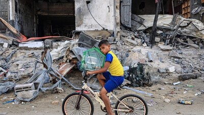 Israel-Hamas War: A Palestinian boy transports his bird on a bicycle past a destroyed building in Rafah in the southern Gaza Strip. (AFP) Israel-Hamas War: A Palestinian boy transports his bird on a bicycle past a destroyed building in Rafah in the southern Gaza Strip. (AFP)