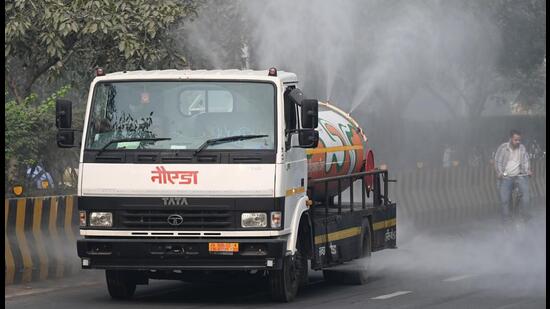 A Noida authority tanker sprays water on roads in Sector 53 to settle the dust on Wednesday. (Sunil Ghosh/HT Photo)