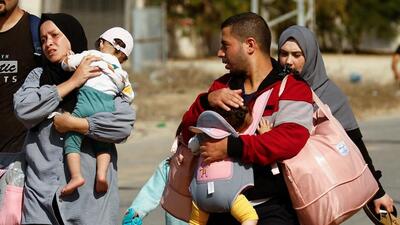 People carry children while Palestinians fleeing north Gaza move southward as Israeli tanks roll deeper into the enclave, amid the ongoing conflict between Israel and Hamas, in the central Gaza Strip (REUTERS)