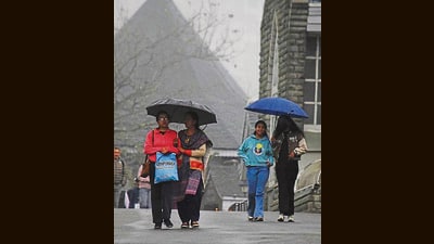 People take stroll during the light rain and cold weather at the Ridge in Shimla on Friday. (Deepak Sansta/HT)
