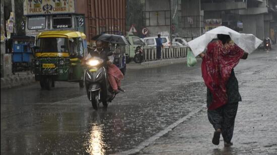 Commuters brave the rain in Amritsar on Friday. (Sameer Sehgal/HT)
