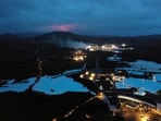 The red shimmer from magma is seen coming out from the erupting Fagradalsfjall volcano behind the tourist landmark Blue Lagoon, near the town of Grindavik on March 20, 2021.
