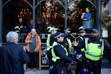 People watch from a pub window as police deploy to contain counter-protesters during a march in solidarity with Palestinians in Gaza in London on November 11, 2023. (Reuters)