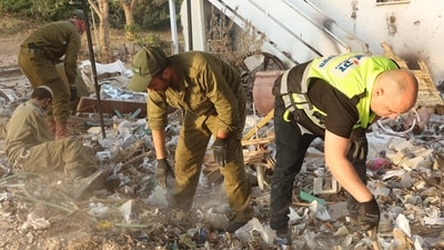 Israeli soldiers and volunteers from the Zaka Israeli ultra-Orthodox Jewish emergency response team searches through the debris in Kibbutz Beeri near the border with Gaza on November 12, 2023, in the aftermath of an attack by Palestinian militants on October 7 (Photo by GIL COHEN-MAGEN / AFP) (AFP)