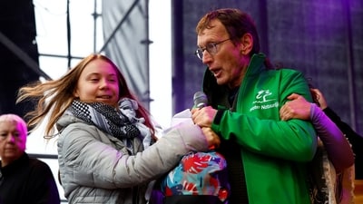 A man holds a microphone with activist Greta Thunberg after he jumped on the stage during her speech as she attends The March for Climate and Justice to demand political change before the elections in Amsterdam, Netherlands, on November 12. (REUTERS)