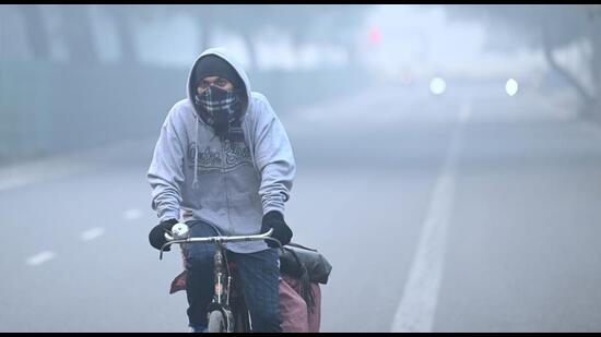 A man covers himself with warm clothes as heavy smog blankets Dwarka on Monday. (Vipin kumar/HT Photo)