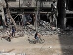 A Palestinian man rides his bicycle past destroyed buildings in Bureij, in the central of Gaza Strip, on November 14, 2023. 